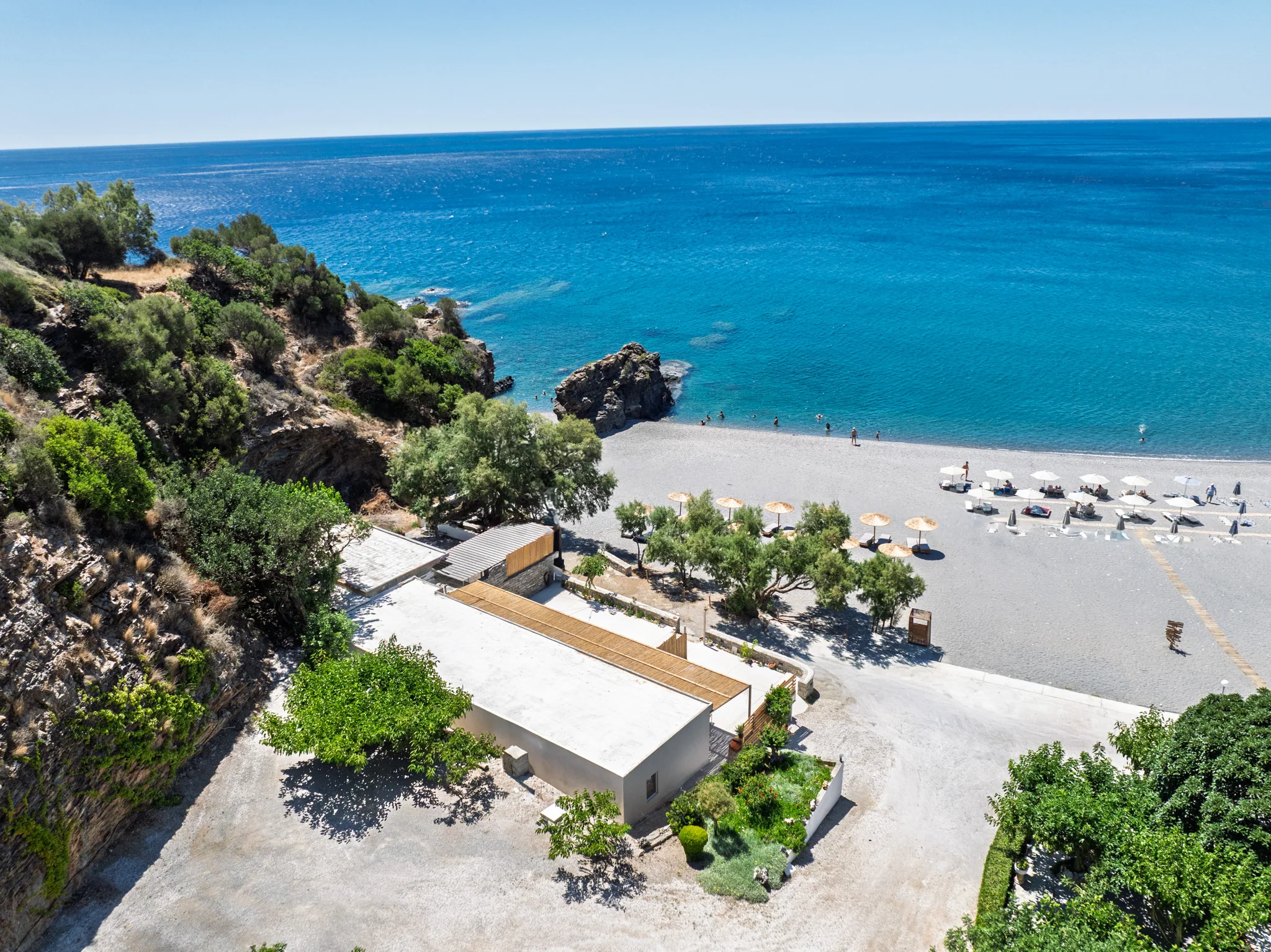 Spilies beneath the rocky eastern point, with the house, pebbled beach and open Libyan Sea in one frame