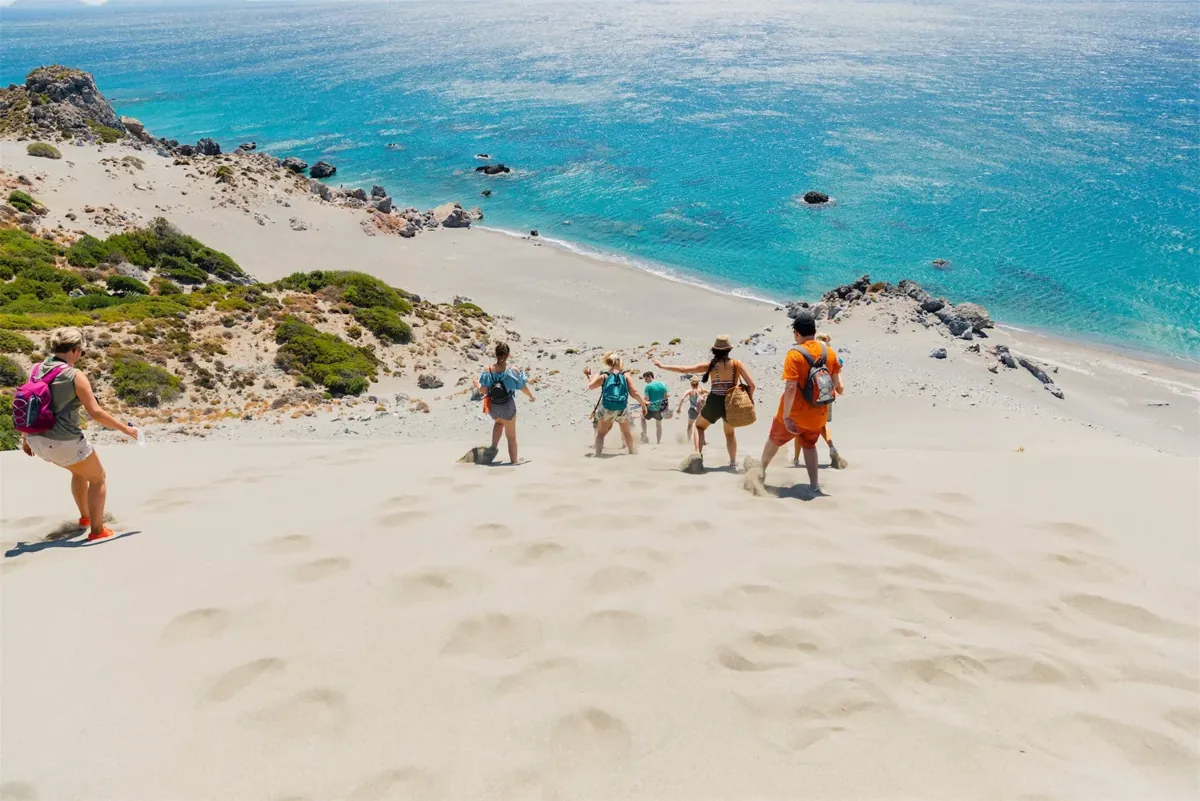 Walkers on the sand dunes above the turquoise bay at Agios Pavlos