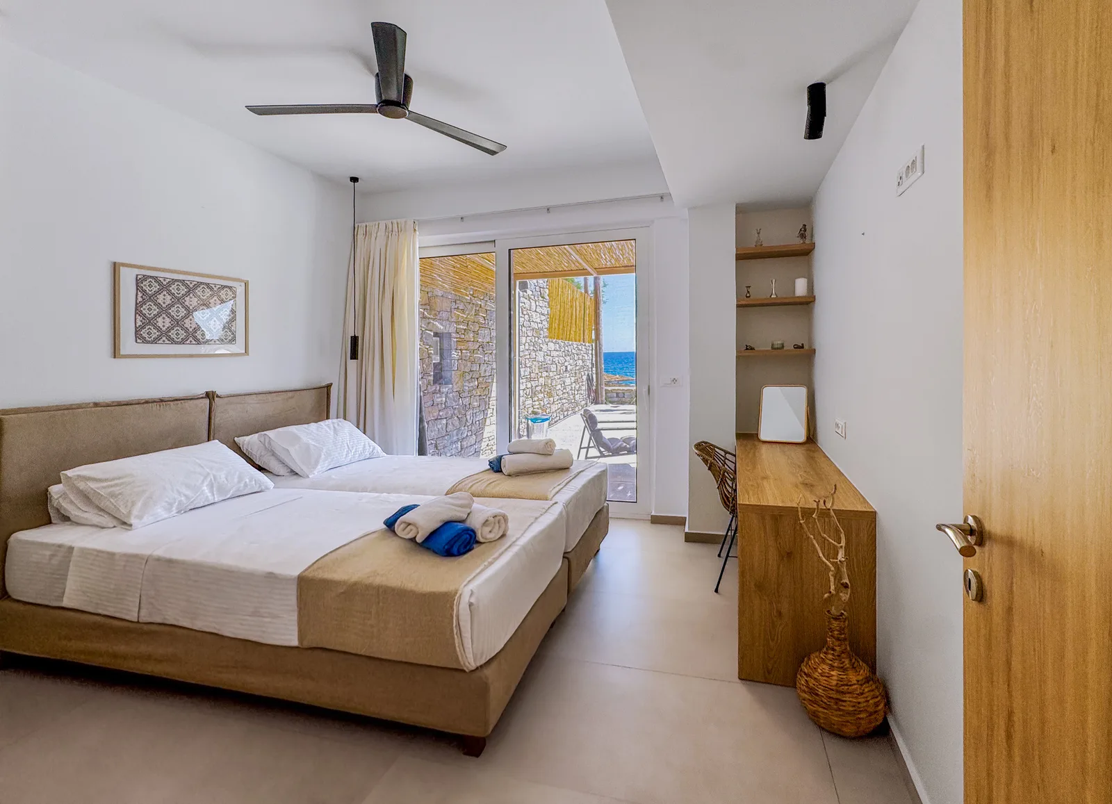 Apartment bedroom with twin beds, desk and the terrace and sea beyond