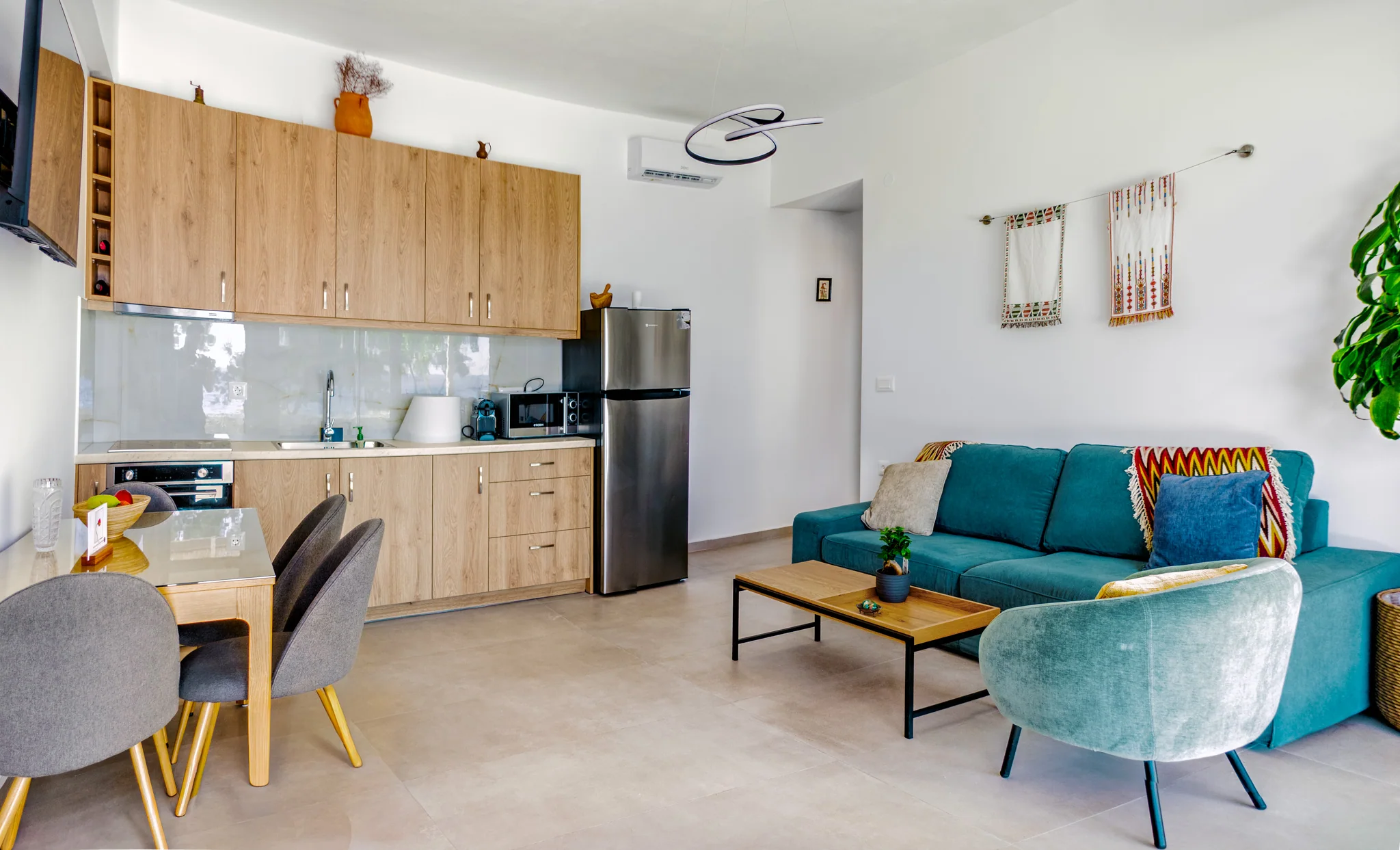The apartment's open living room with its full oak kitchen, dining table, teal sofa and armchairs