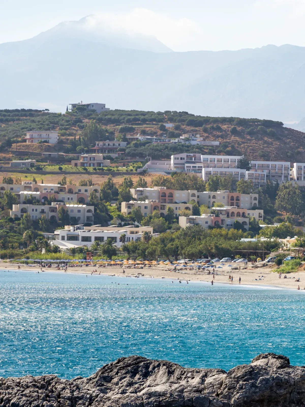 Damnoni: houses on the hill above the bay, the beach and the sea below, mountains behind
