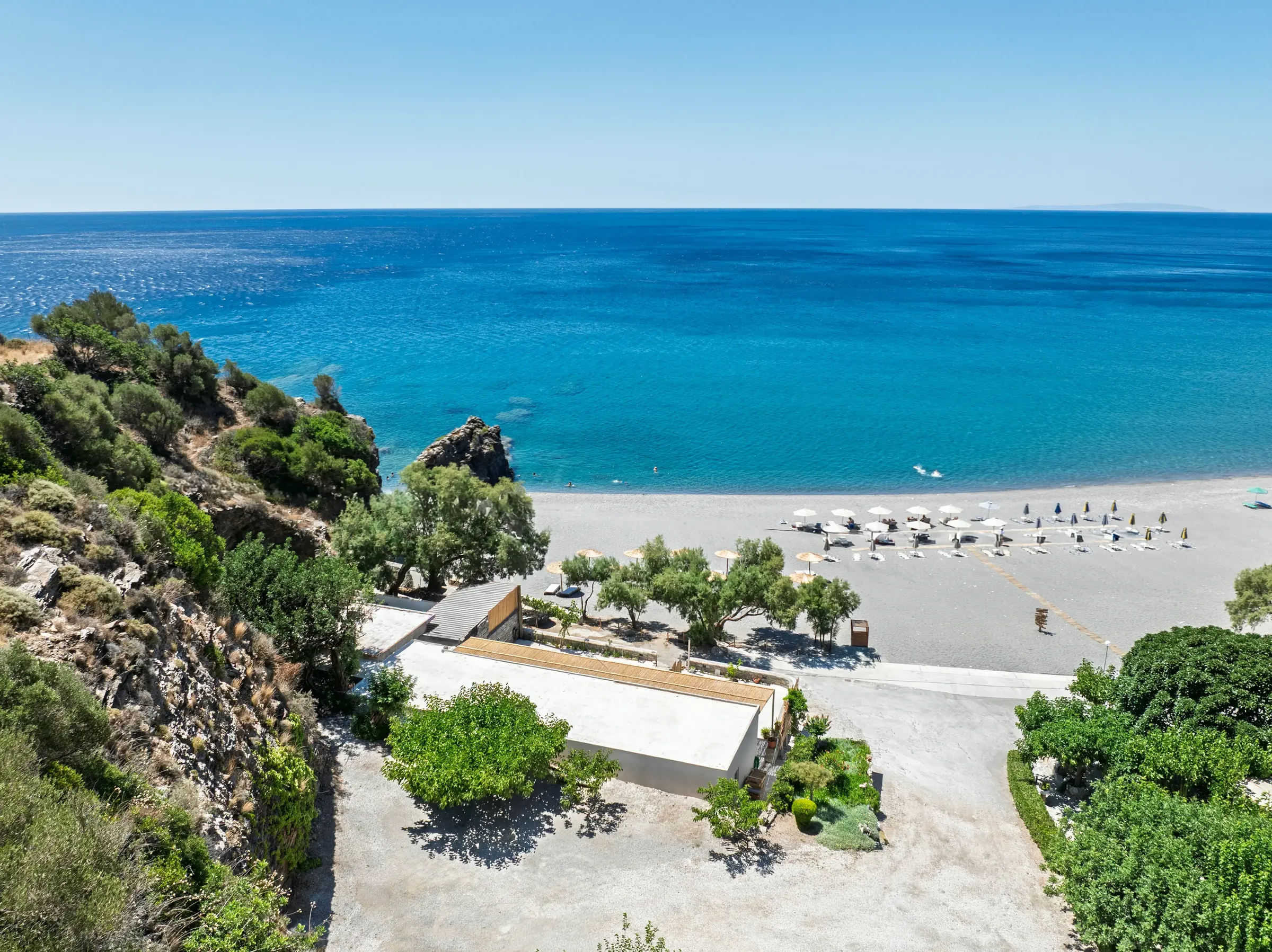 High behind the house: the terrace roof, the trees, the whole beach and a wide sea under the sky