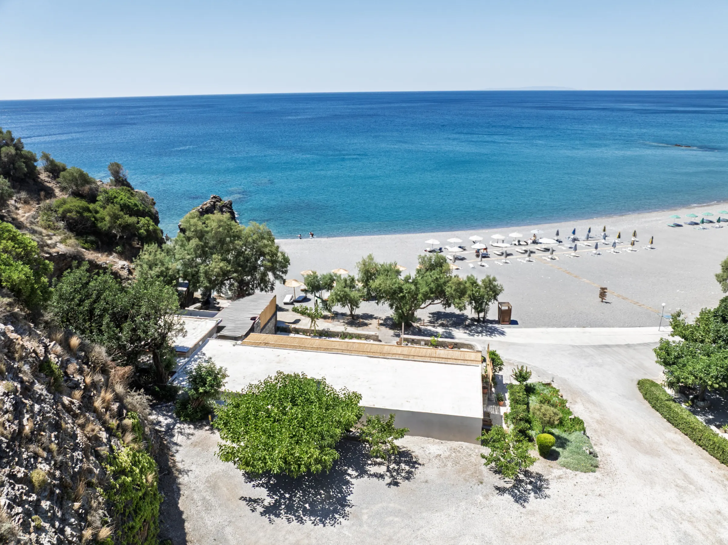 Looking down over Korakas bay from the cliff — the beach curving along the turquoise water