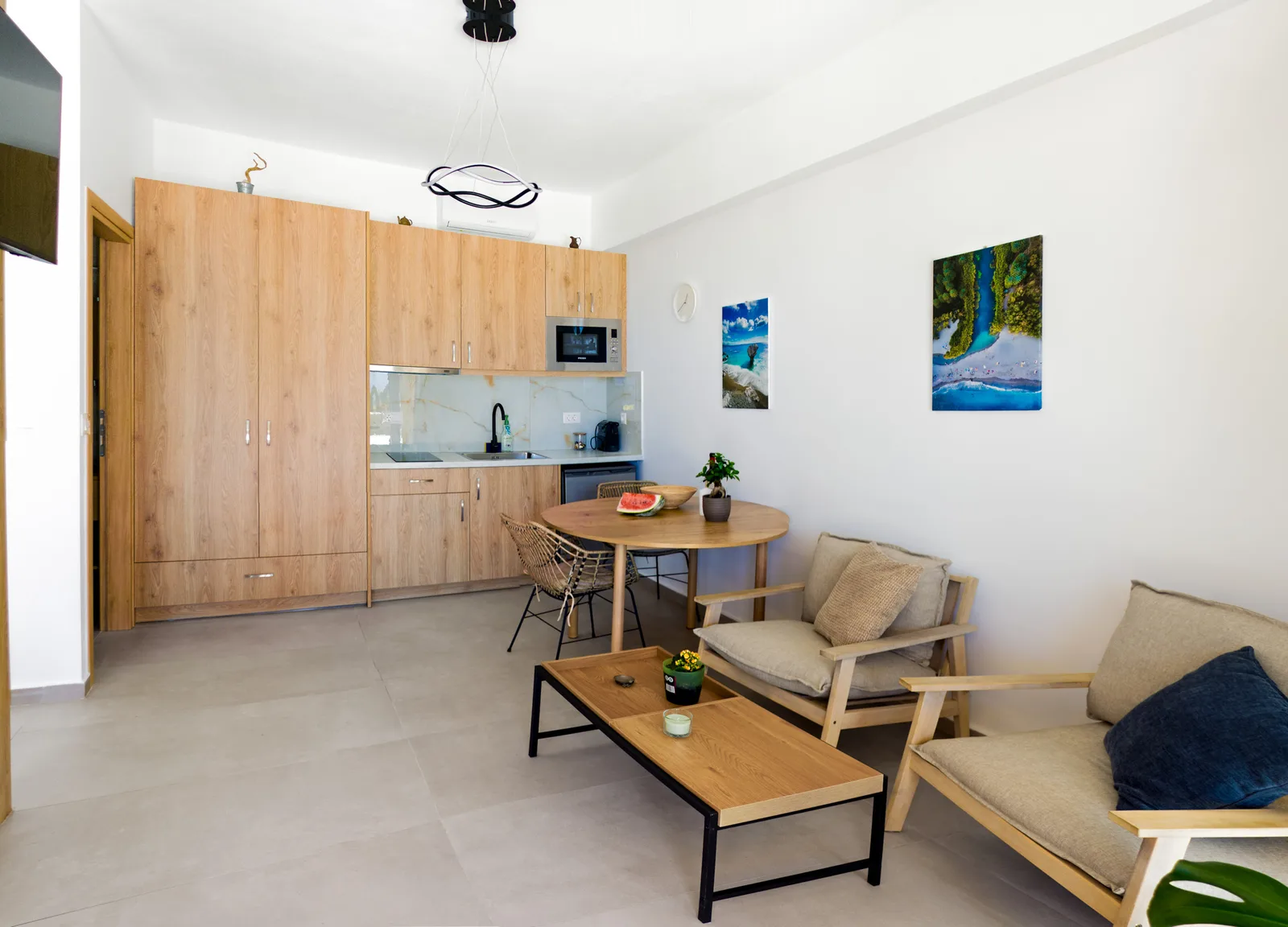 The studio kitchenette, dining table and lounge beneath framed views of the coast