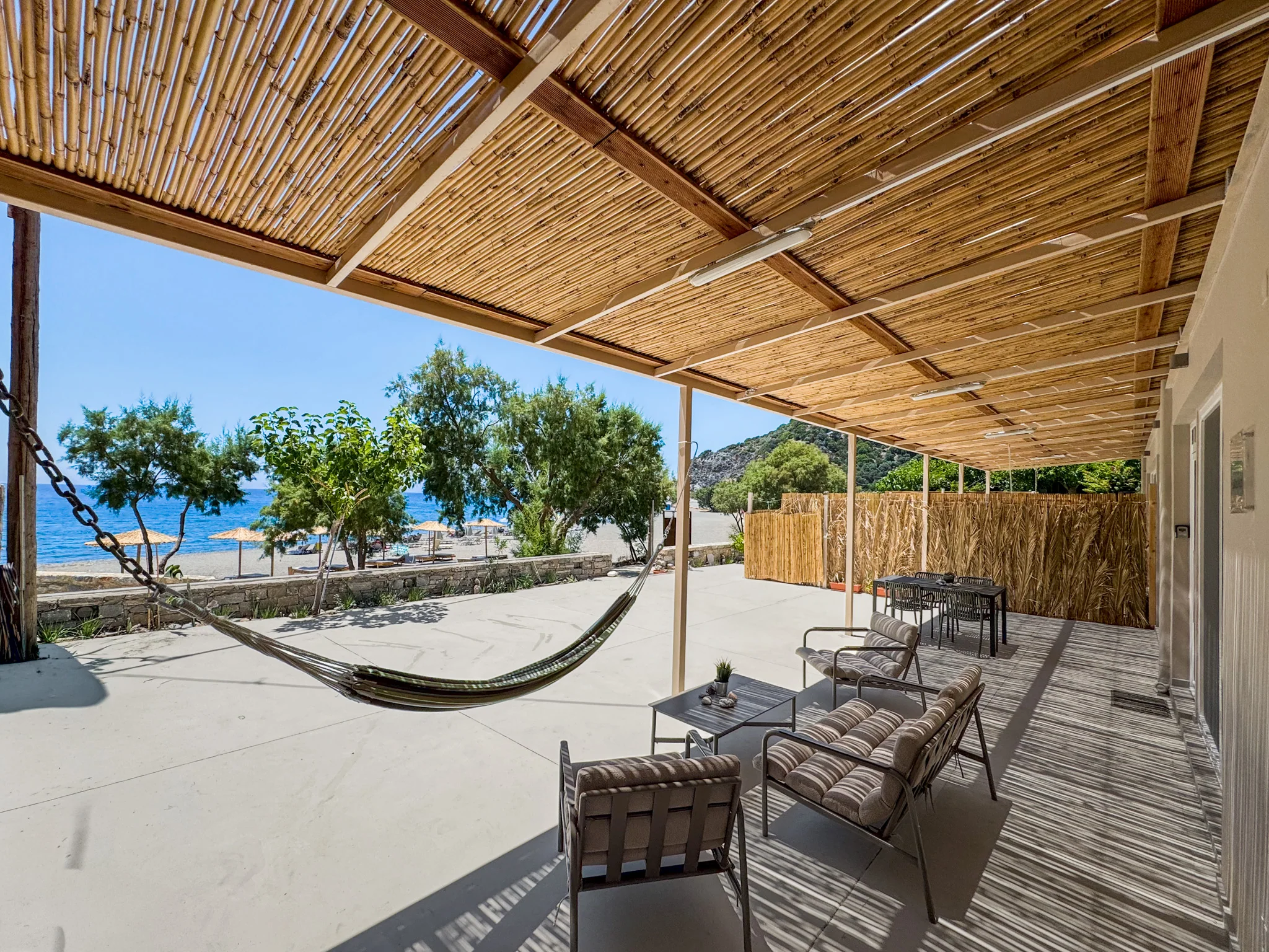 The bamboo-shaded terrace with hammock and chairs facing the sea
